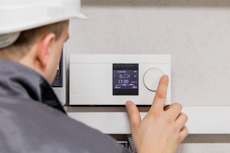 Engineer,Adjusting,Thermostat,For,Efficient,Automated,Heating,System Hvac Building Automation Houston