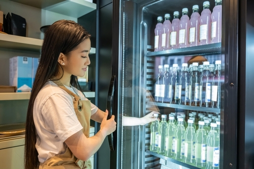 Coffee,Shop,Employee,Reaching,For,A,Bottle,In,The,Fridge Reach In Stock